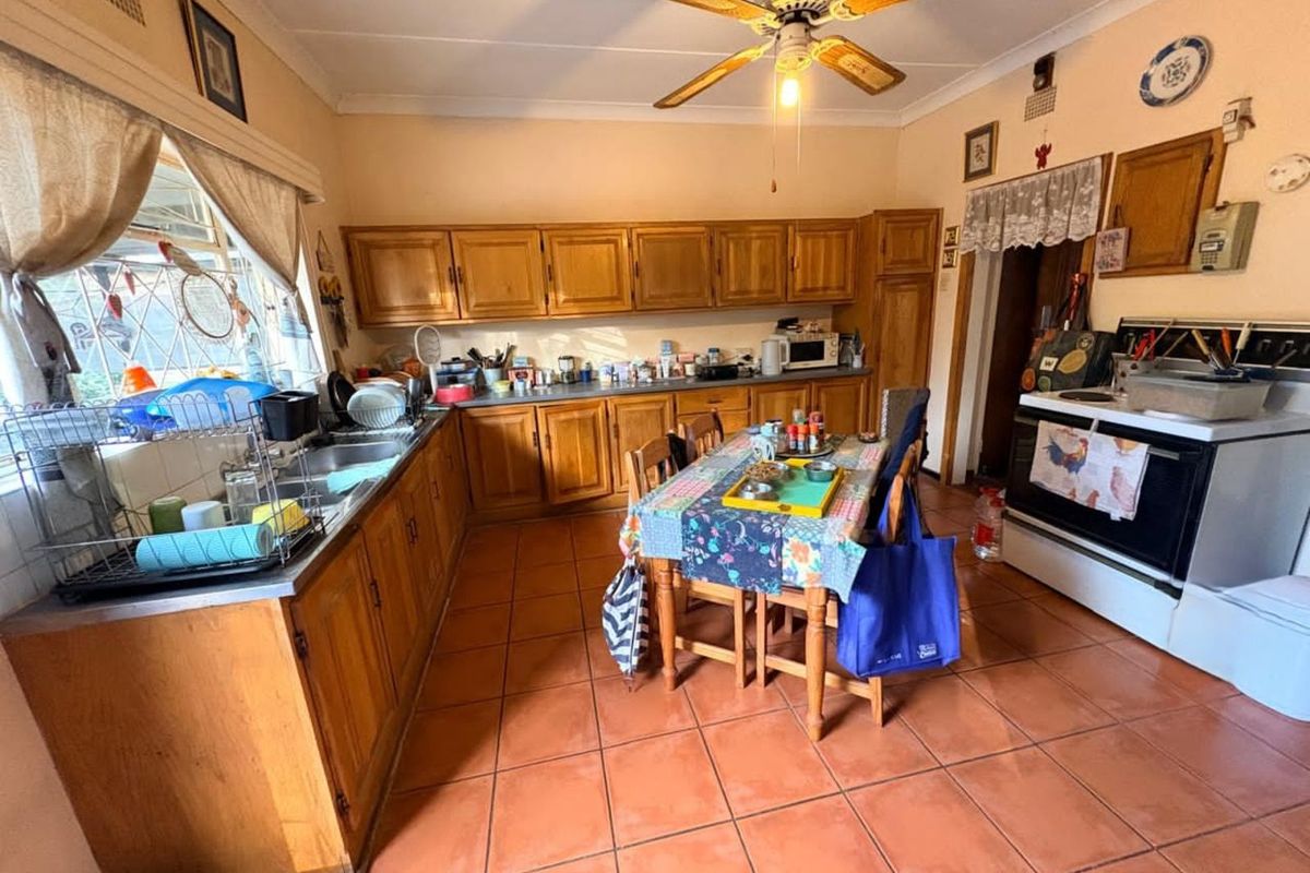 A functional kitchen featuring timber cabinetry, tiled flooring, a ceiling fan, and a freestanding stove, offering a traditional layout with ample storage space.