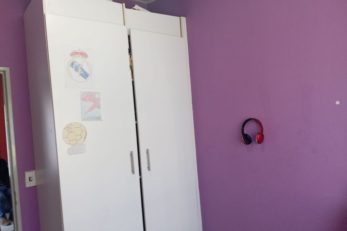 A bedroom featuring a built-in white wardrobe against a purple painted wall.