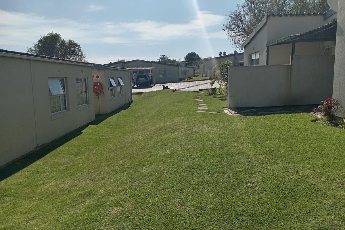 A view of the communal garden area between townhouse units, featuring manicured lawns and paved pathways.