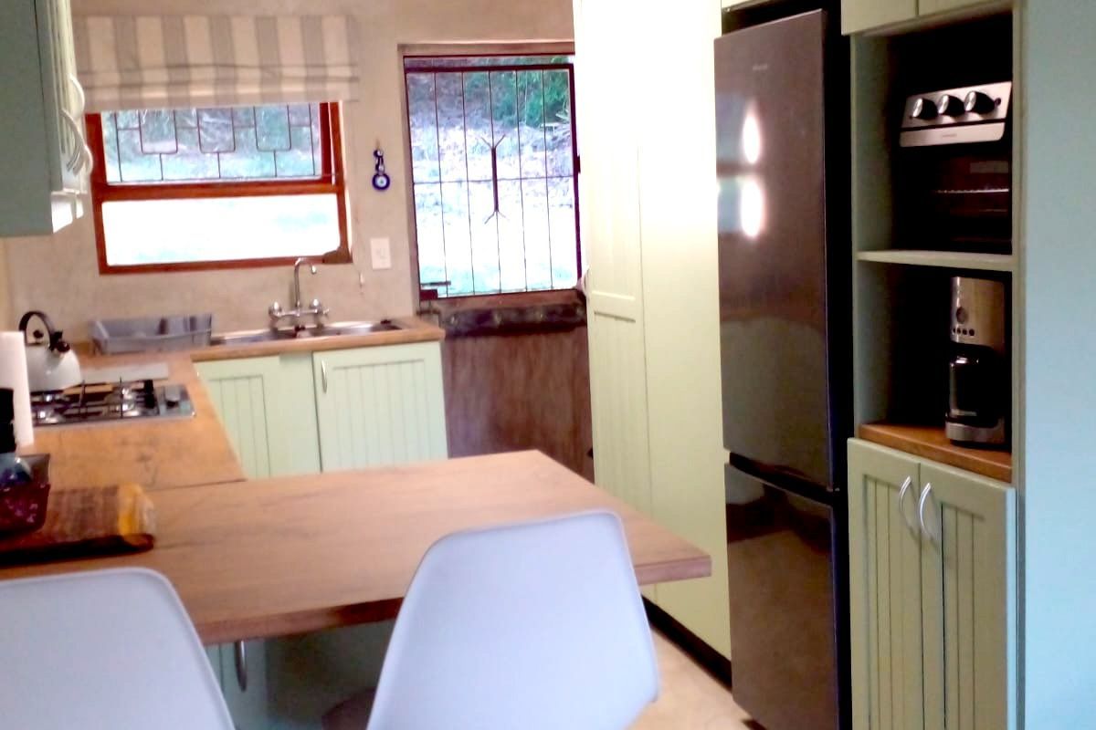 A functional kitchen featuring light green cabinetry, wooden countertops, a built-in oven, and a breakfast bar area with direct access to the exterior.