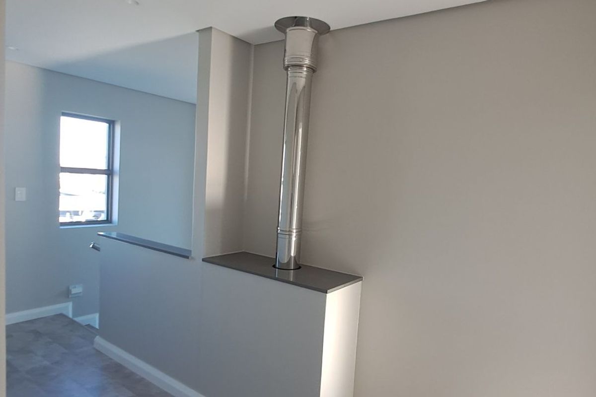 A bright interior space featuring a modern stainless steel fireplace flue integrated into a built-in partition wall.
