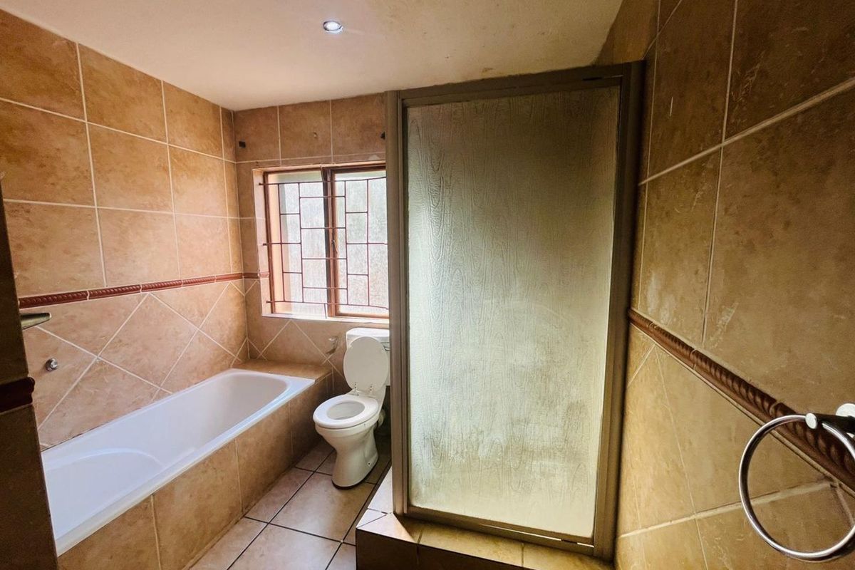 A functional bathroom featuring a built-in bathtub, a separate shower enclosure with a frosted screen, and a standard toilet.