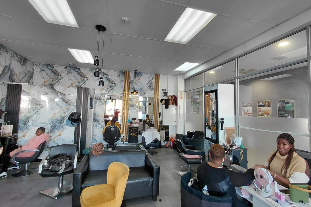 A functional retail salon space featuring marble-effect wall cladding, recessed ceiling lighting, and glass partition walls, suitable for hair and beauty services.