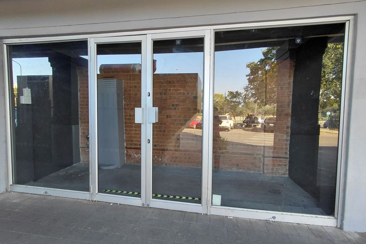 Retail storefront entrance featuring large glass display windows and a central double-door entry with aluminum framing.
