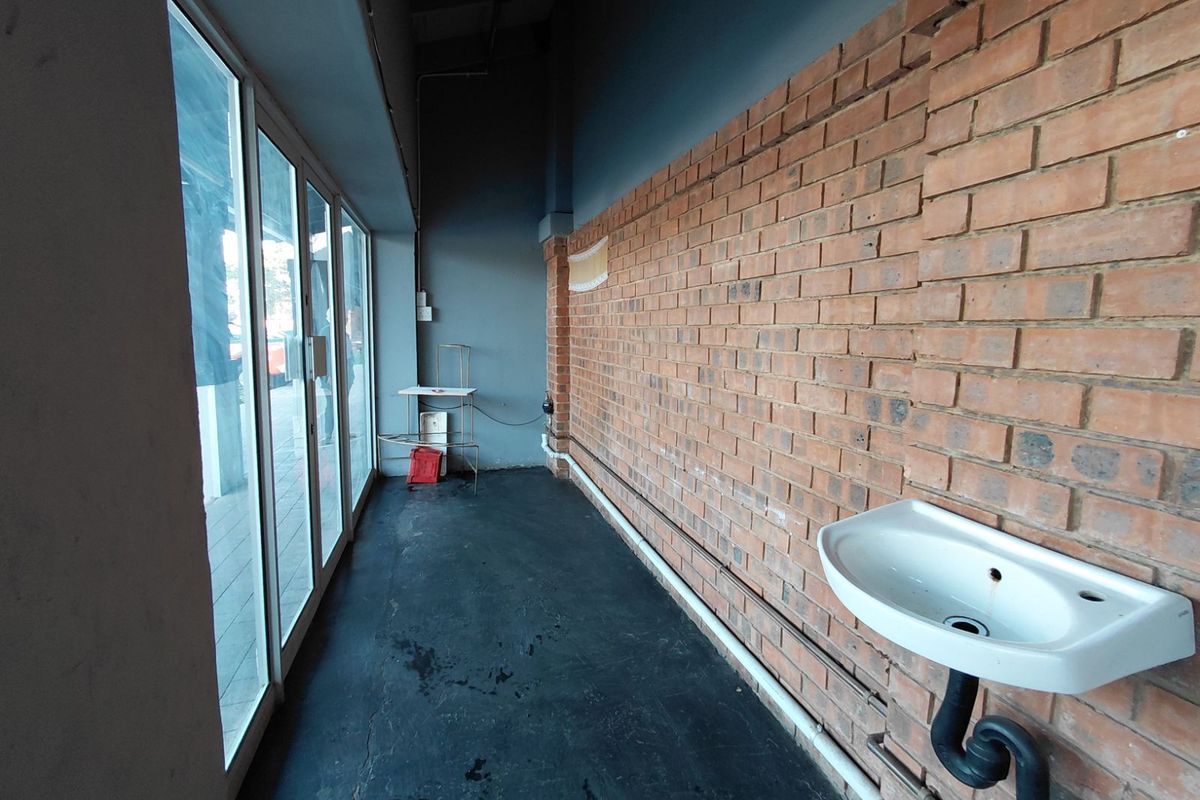 A functional utility space featuring an exposed brick wall, a wall-mounted basin, and large glass panel windows providing natural light.