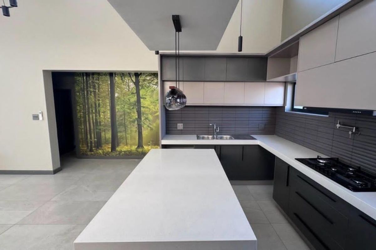 Modern open-plan kitchen featuring a large central island, sleek cabinetry, integrated gas hob, and contemporary tiled backsplash.