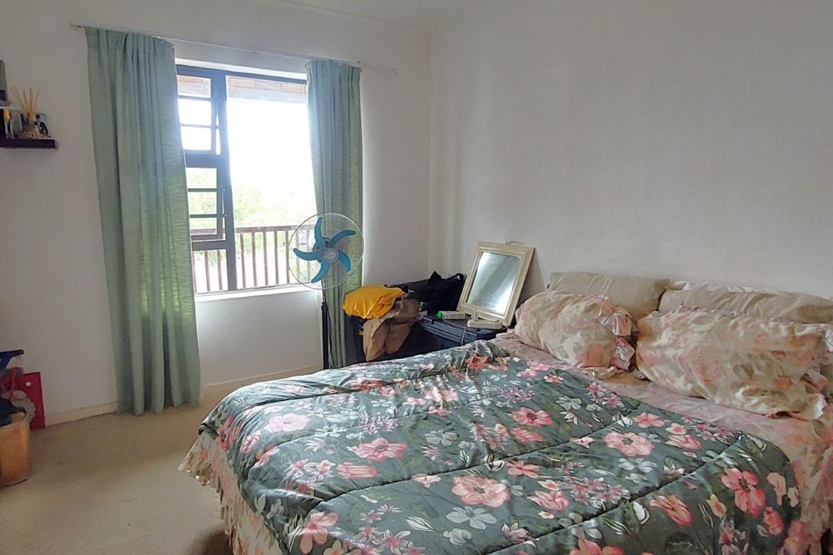 A functional bedroom featuring built-in wardrobe storage, carpeted flooring, and a window providing natural light.