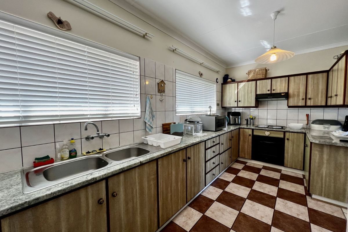 A functional kitchen featuring laminate countertops, built-in cabinetry, a double-basin sink, and integrated oven with extractor fan.