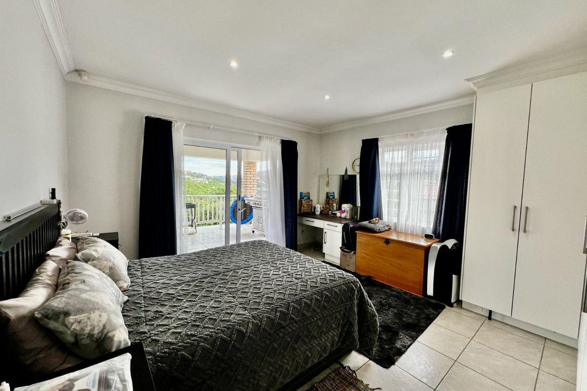 Spacious bedroom featuring built-in cupboards, tiled flooring, recessed lighting, and sliding glass doors providing direct access to a private balcony with scenic views.