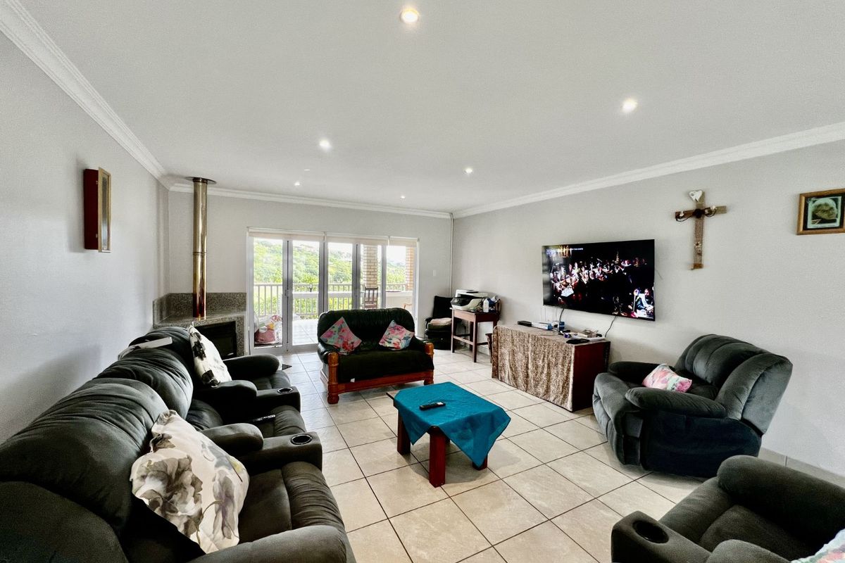Spacious living room featuring tiled flooring, recessed downlighting, a built-in fireplace with a flue, and sliding glass doors leading to an outdoor balcony.