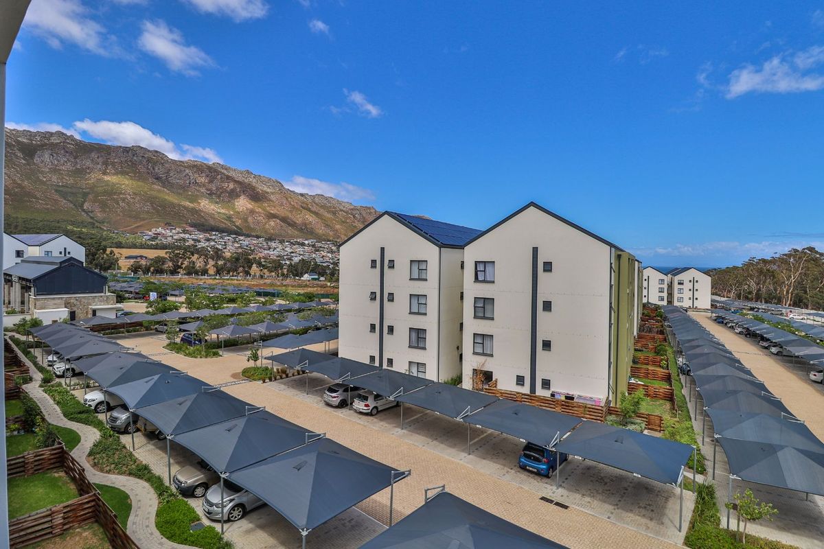 Elevated aerial view of the apartment complex featuring modern multi-story buildings, paved parking areas with shade-cloth carports, and surrounding landscaped grounds.