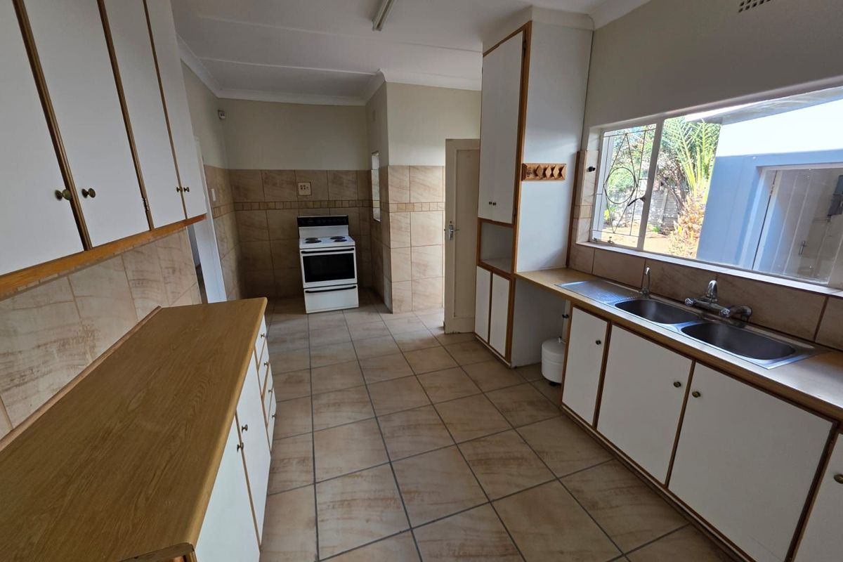 A functional kitchen featuring tiled flooring, ample cabinetry, a double-basin sink, and a freestanding stove, offering a practical layout for daily meal preparation.