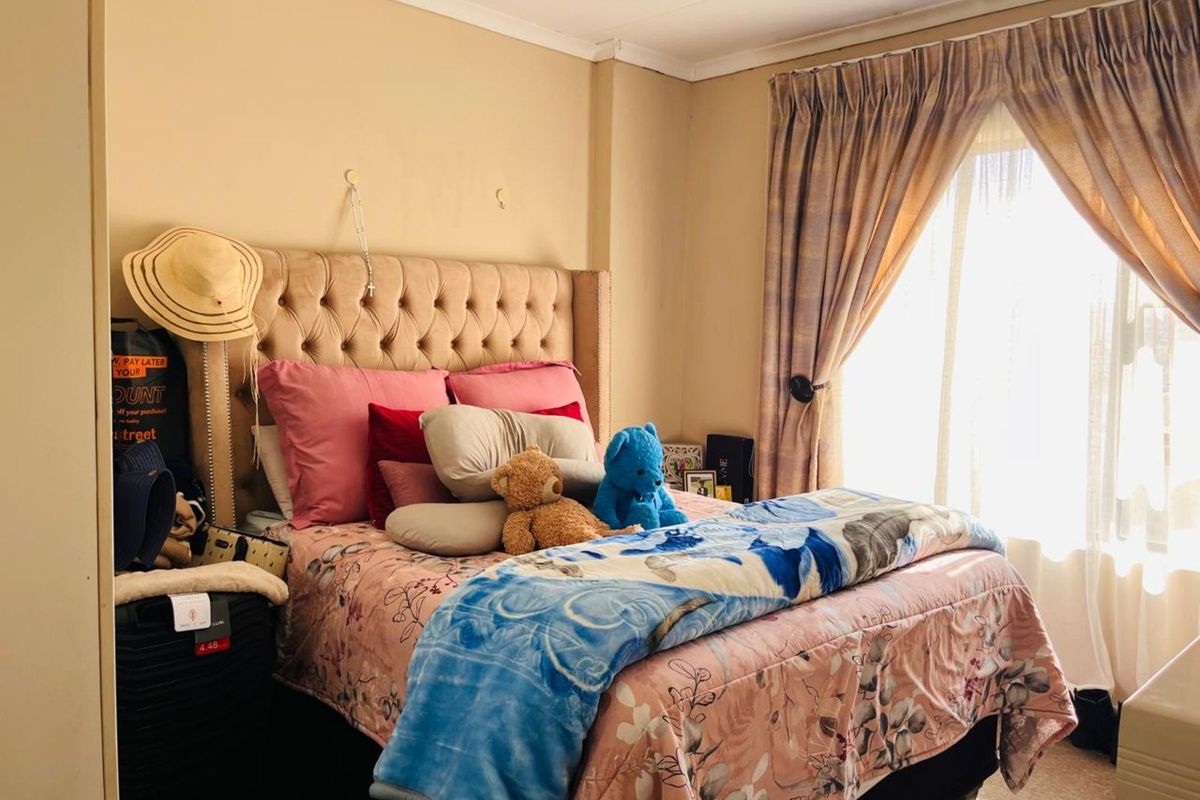 A cozy bedroom featuring a tufted headboard, neutral wall tones, and natural light filtering through window curtains.