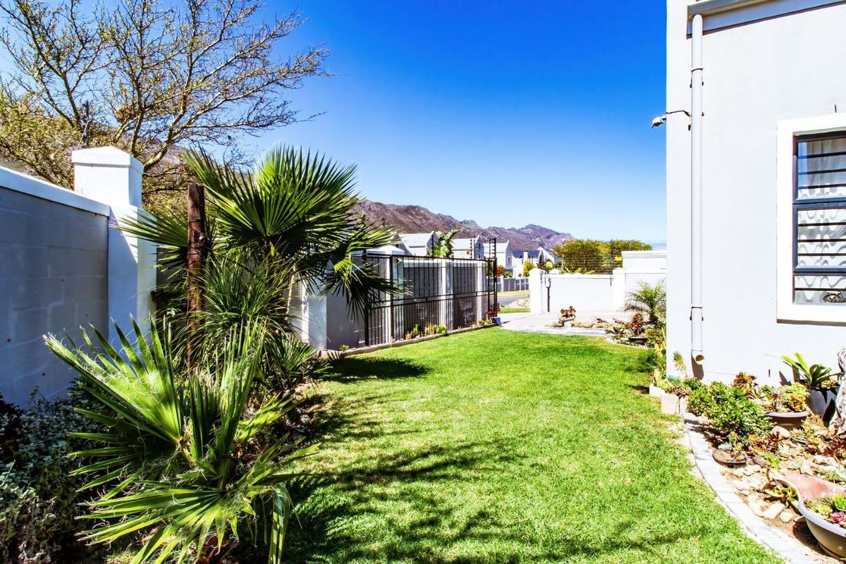 A well-maintained rear garden area featuring a manicured lawn, perimeter boundary walls, and established landscaping, providing a private outdoor space.
