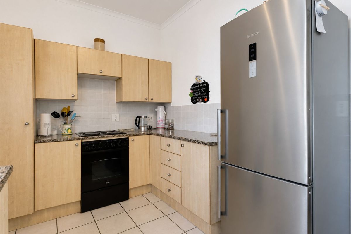A functional kitchen featuring light wood cabinetry, granite countertops, tiled backsplash, and a built-in oven with hob.