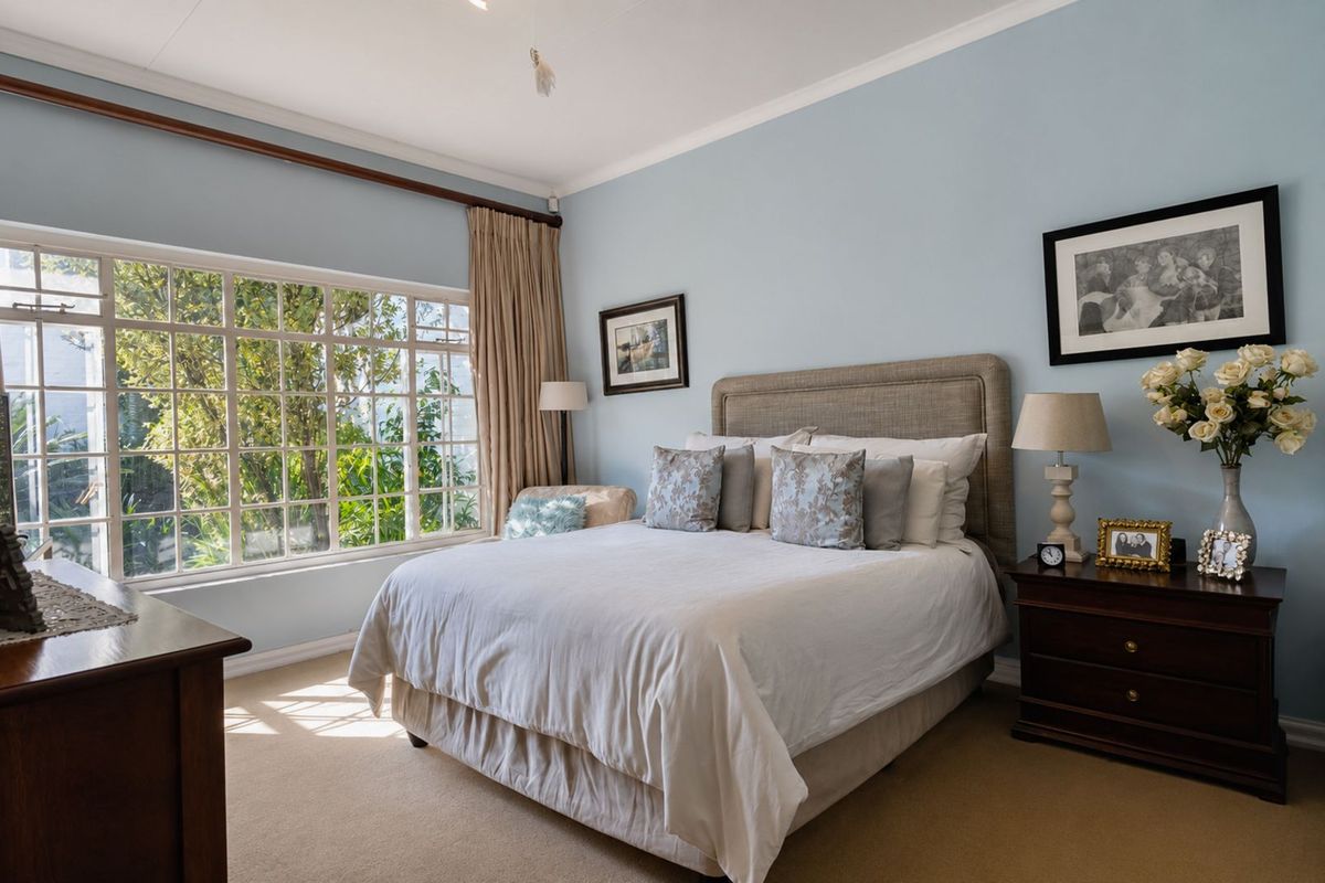 A well-lit bedroom featuring large paneled windows, neutral carpeting, and classic crown molding, offering a comfortable and inviting living space.