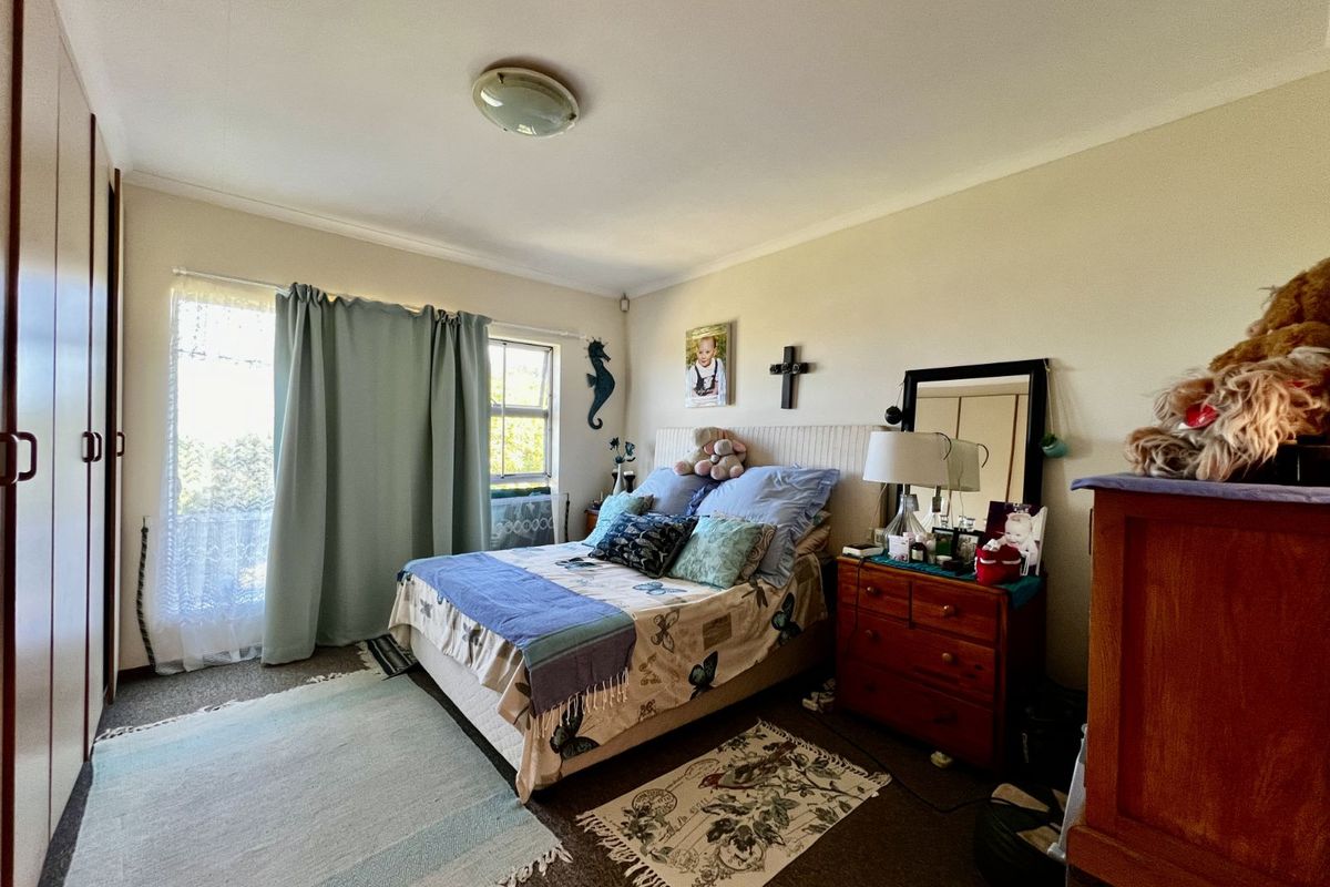 A bedroom featuring built-in cupboards, carpeted flooring, and a window with natural light, providing a functional and comfortable living space.