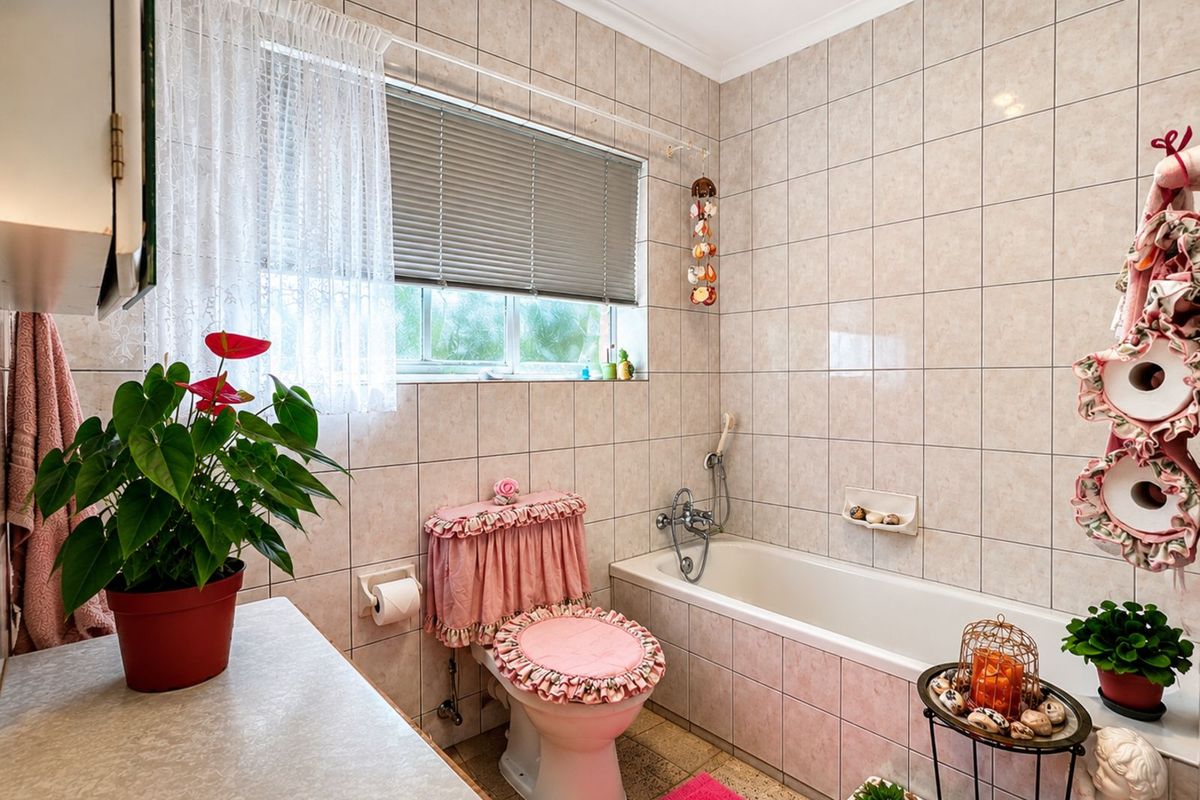 A functional bathroom featuring a built-in bathtub with shower mixer, tiled walls, and a window with fitted blinds.