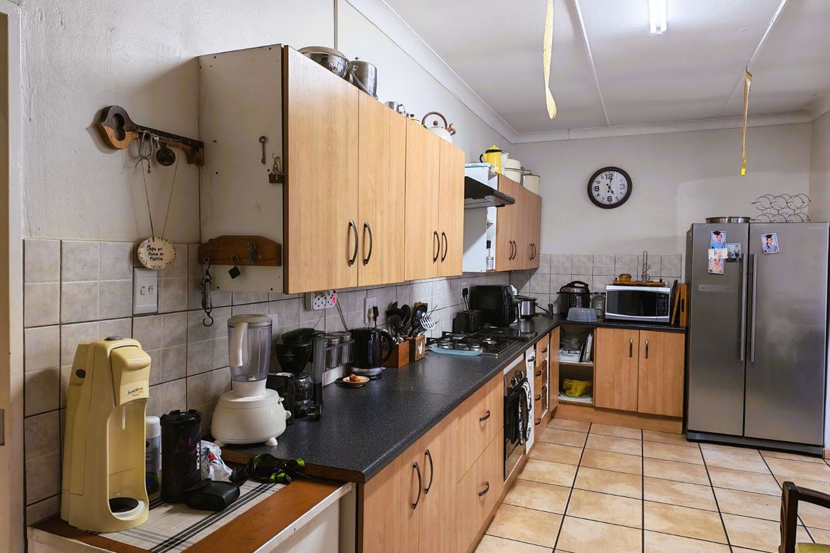 Functional kitchen featuring laminate cabinetry, dark countertops, tiled flooring, and a tiled backsplash, providing a practical workspace for daily meal preparation.
