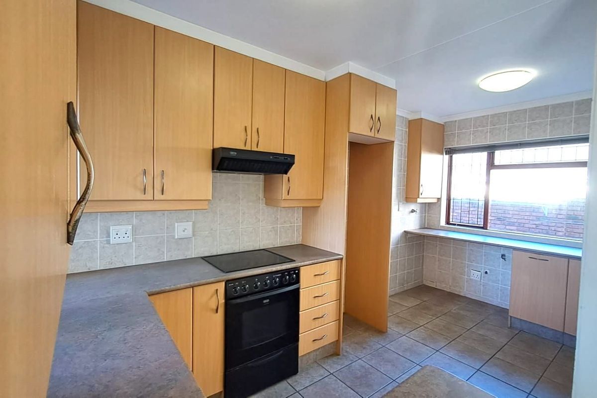 Functional kitchen featuring light wood cabinetry, tiled splashbacks, built-in oven with hob, and tiled flooring with ample counter space.