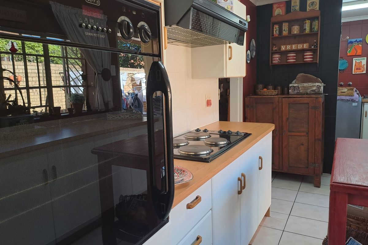 A functional kitchen featuring a built-in Defy oven, electric hob, extractor fan, and tiled flooring with ample cabinetry.