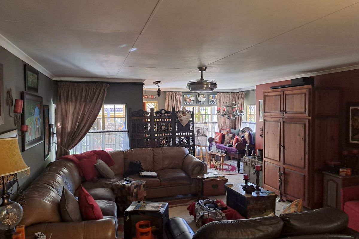 Spacious living area featuring tiled flooring, a ceiling fan, and large windows allowing for natural light.