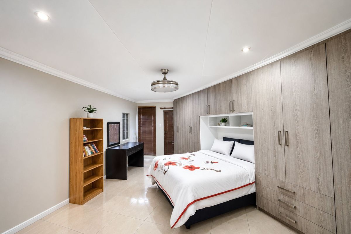 A well-maintained bedroom featuring extensive built-in cabinetry, recessed ceiling lighting, tiled flooring, and a ceiling fan.