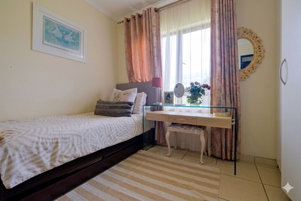A compact bedroom featuring tiled flooring and a window with curtain treatments, providing a functional and well-lit living space.