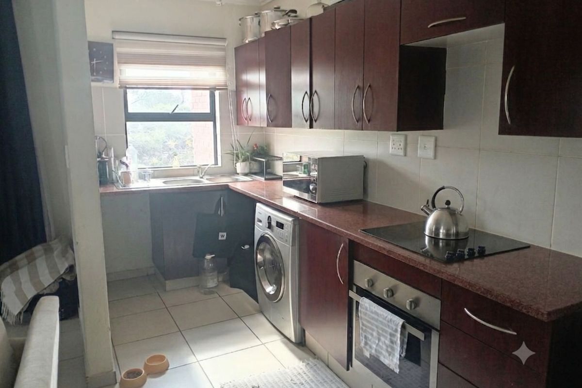 A functional kitchen featuring dark wood cabinetry, granite countertops, a built-in oven, electric hob, and tiled flooring with an integrated laundry space.