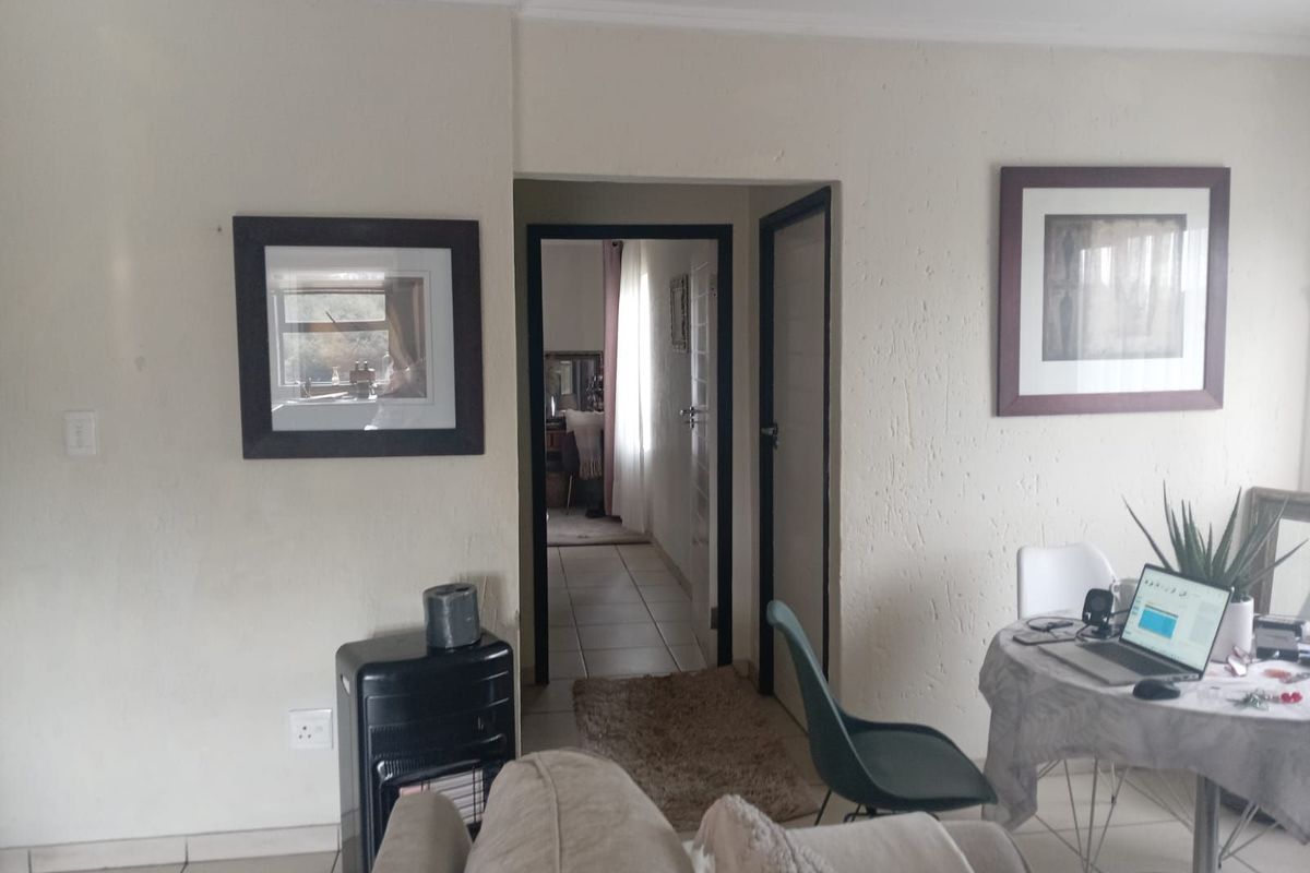 A view of the living area looking through to a hallway, featuring tiled flooring and neutral wall finishes.