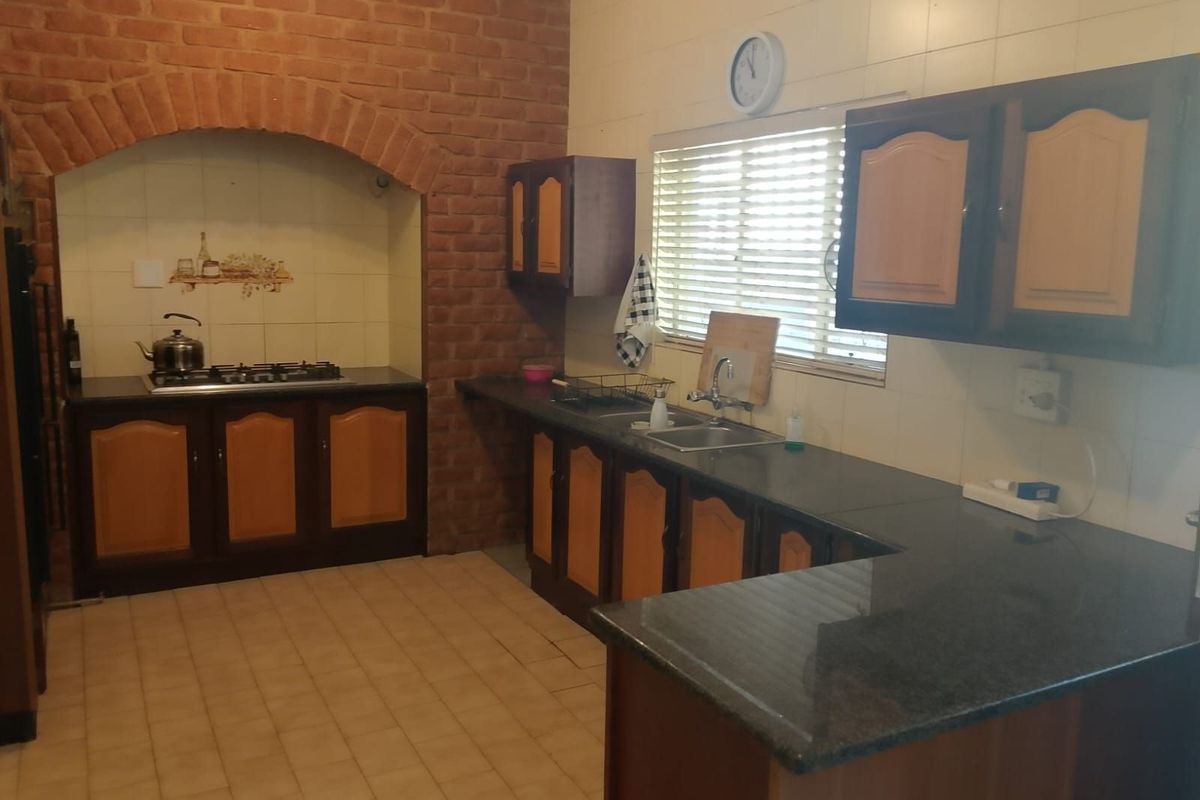 A functional kitchen featuring a brick-arched stove alcove, dark granite countertops, and traditional wooden cabinetry with ample workspace.