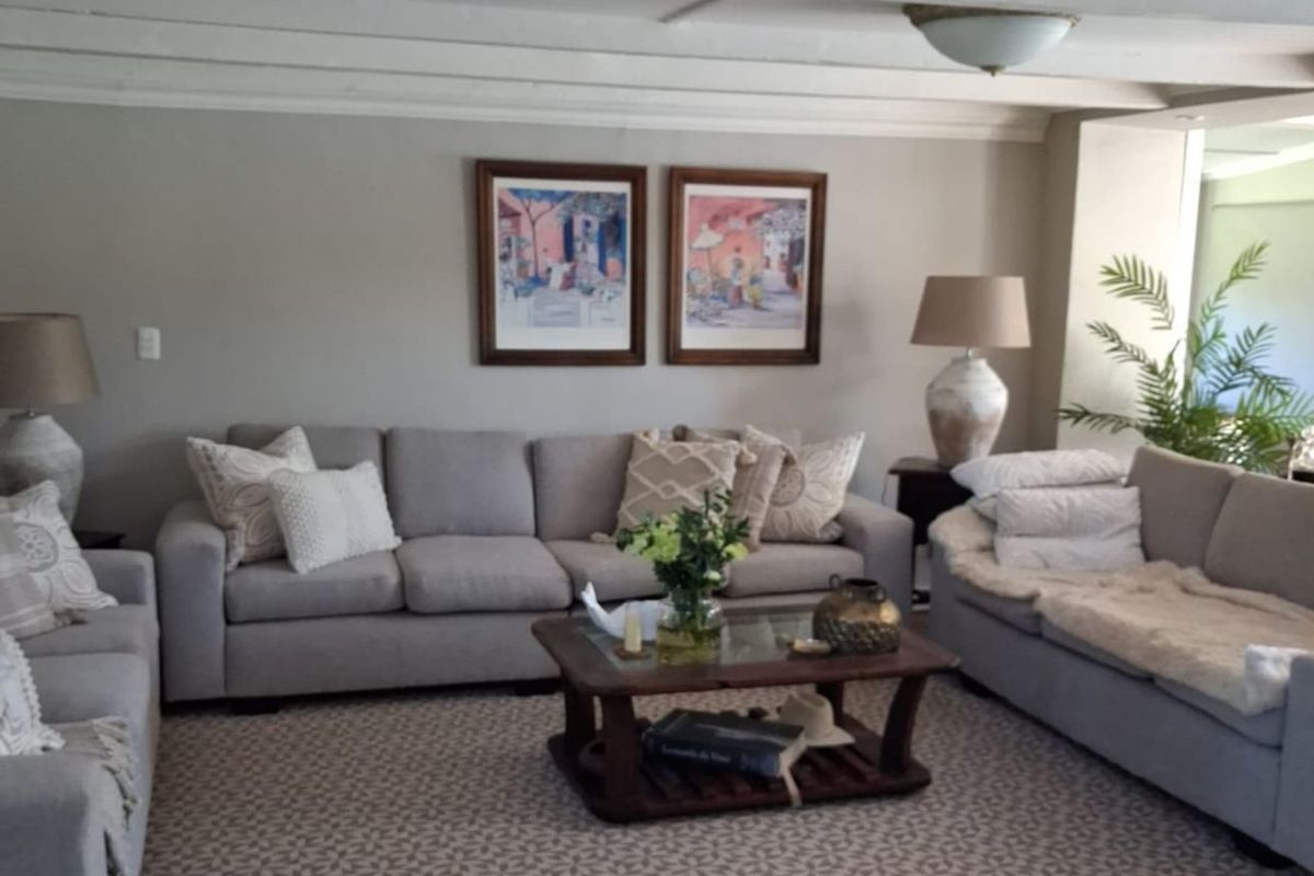 A comfortable living room featuring exposed white ceiling beams and neutral wall tones, creating a bright and inviting space for relaxation.