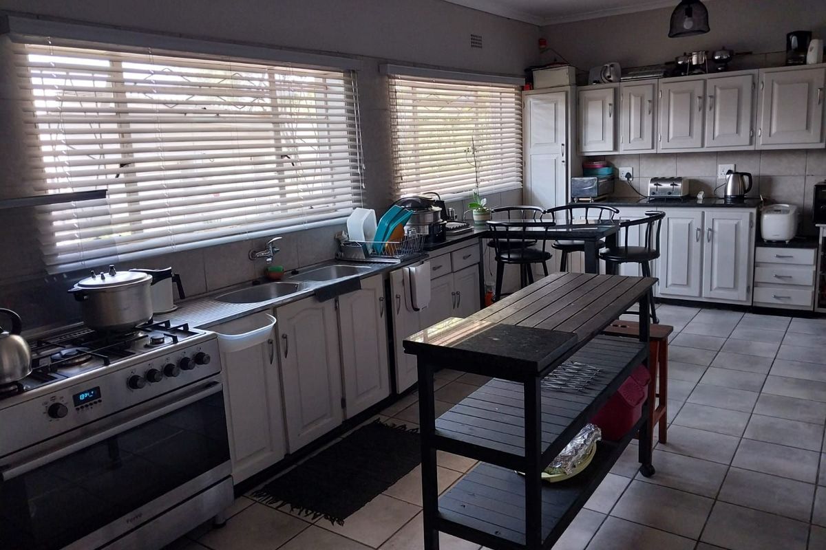 A functional kitchen featuring white cabinetry, tiled flooring, a gas stove, and ample natural light from large windows with fitted blinds.