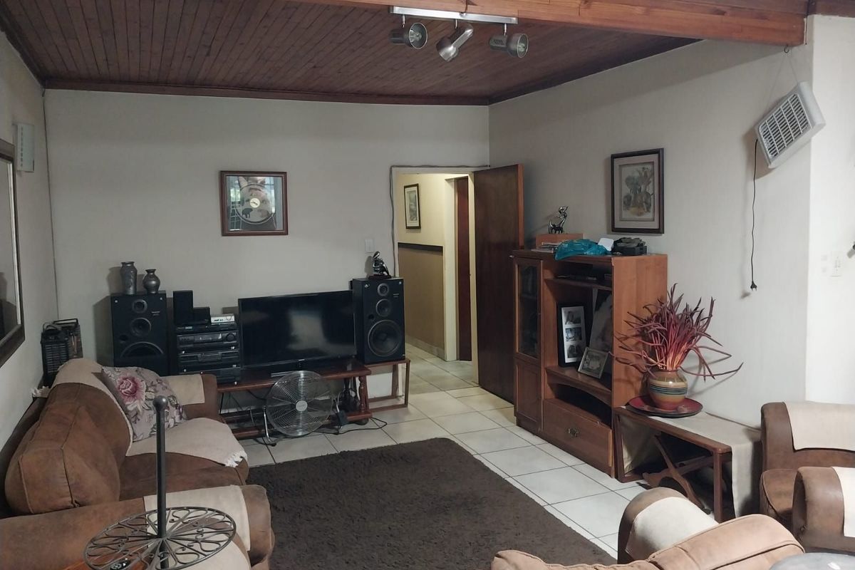 A living room featuring tiled flooring and a timber-clad ceiling with integrated track lighting.