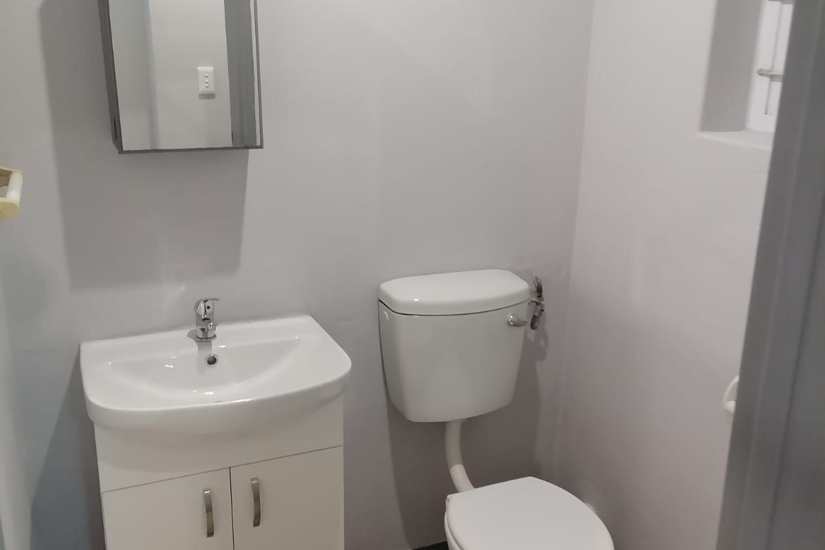 A clean and functional guest bathroom featuring a modern vanity cabinet, basin, and toilet with wood-look flooring.