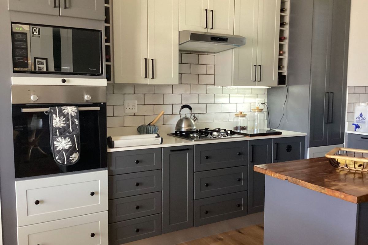 Modern kitchen featuring two-tone cabinetry, subway tile backsplash, built-in oven, microwave, and gas hob with extractor fan.