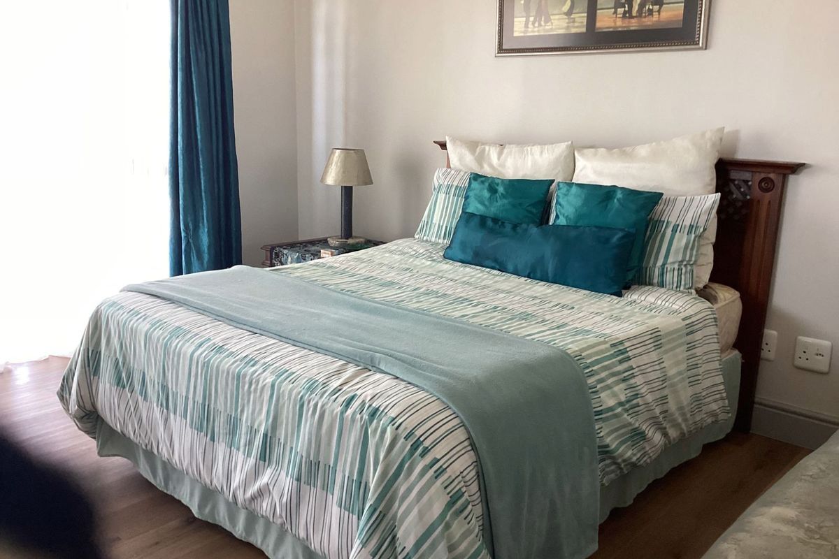 A well-maintained bedroom featuring laminate flooring and a large window with curtains, providing a comfortable and functional living space.