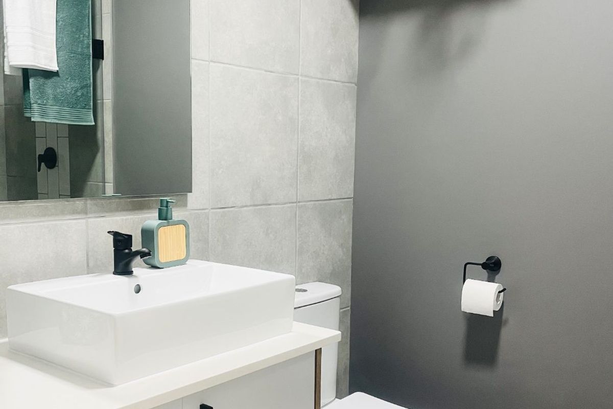 Modern bathroom featuring a sleek vanity with a vessel sink, matte black fixtures, large wall mirror, and contemporary grey tiling.