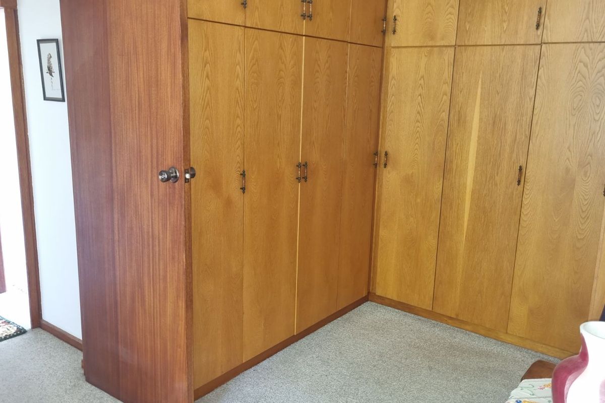 A bedroom featuring extensive floor-to-ceiling built-in wooden cabinetry providing ample storage space.