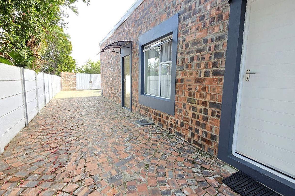 Side exterior view of the property featuring exposed brickwork, paved driveway, and secure access doors.