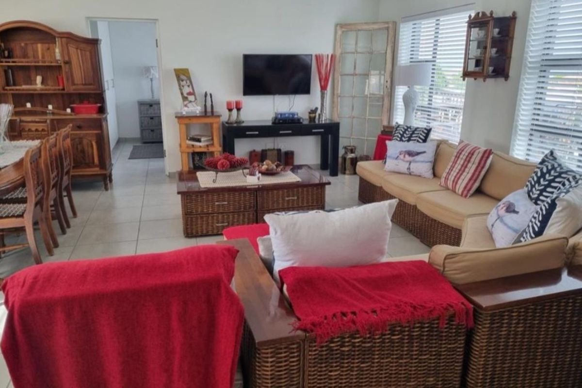 A spacious living area featuring neutral floor tiles and large windows with fitted blinds, providing a bright and functional open-plan living space.