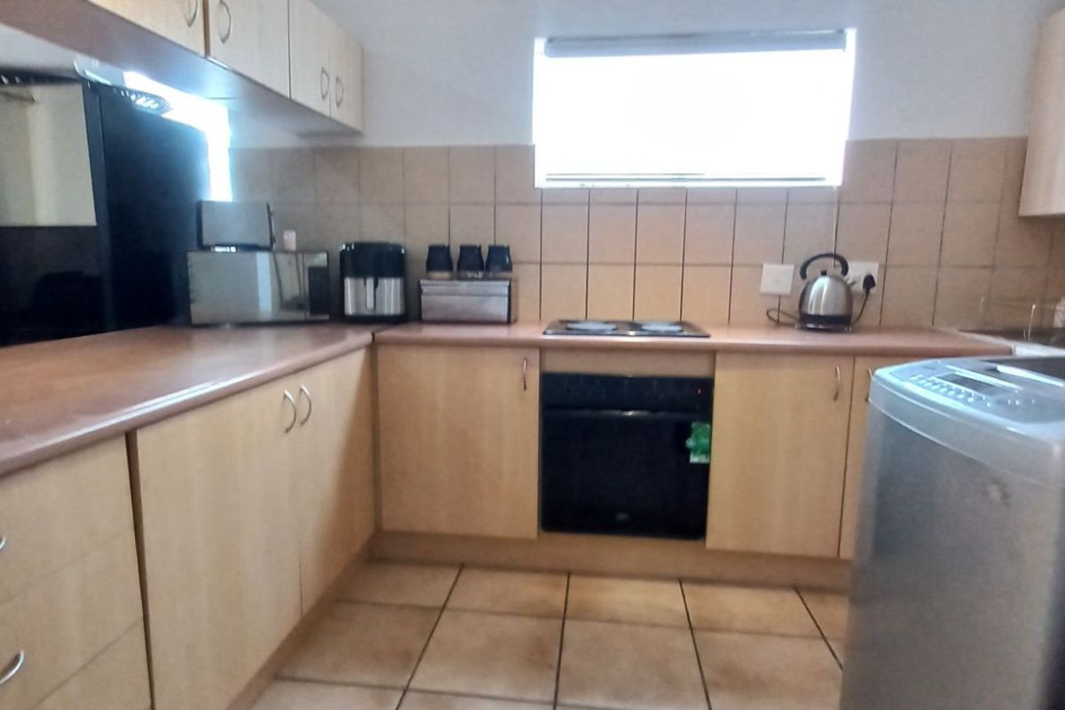 A functional kitchen featuring light wood cabinetry, a built-in oven with hob, tiled flooring, and a tiled backsplash.