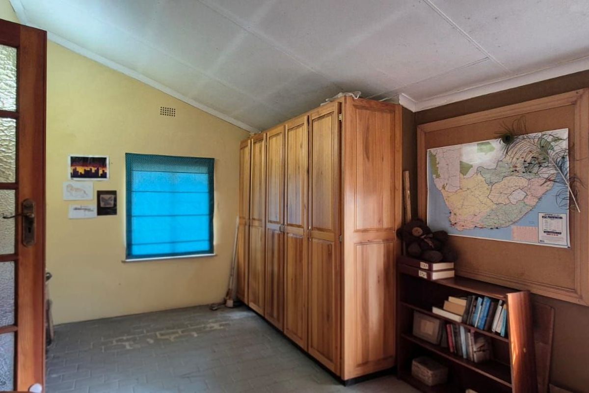 A bedroom featuring built-in wooden cabinetry, tiled flooring, and natural light through windows with roller blinds.