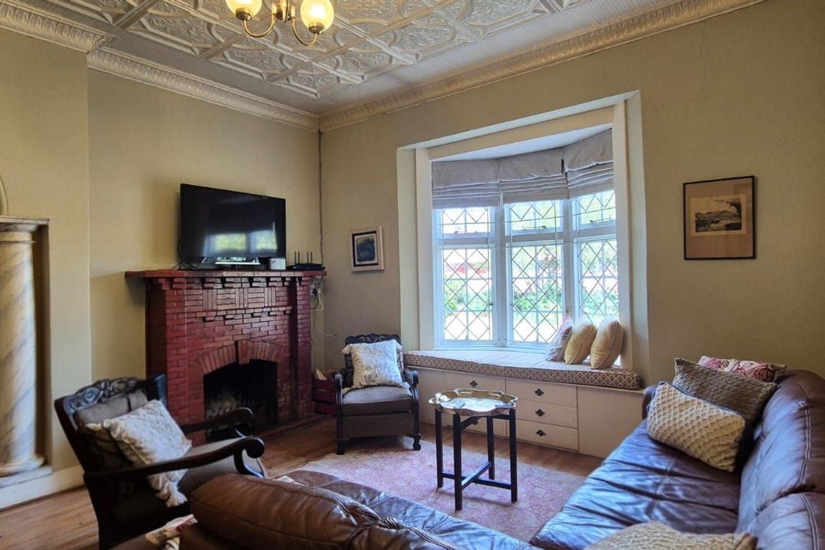 A character-filled living room featuring a classic brick fireplace, ornate pressed metal ceiling, and a charming bay window with built-in seating.