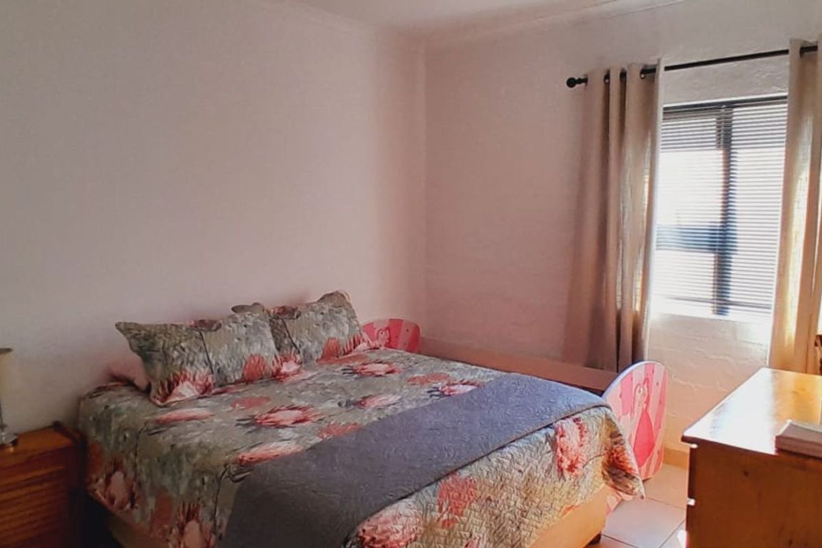 A standard bedroom featuring tiled flooring and a window with fitted curtain rods.