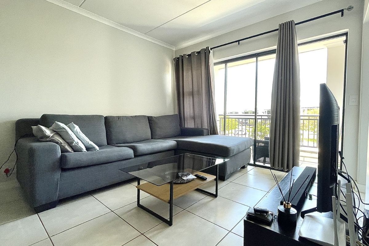 A bright living room featuring large sliding glass doors that open onto a balcony, providing natural light and access to outdoor space.
