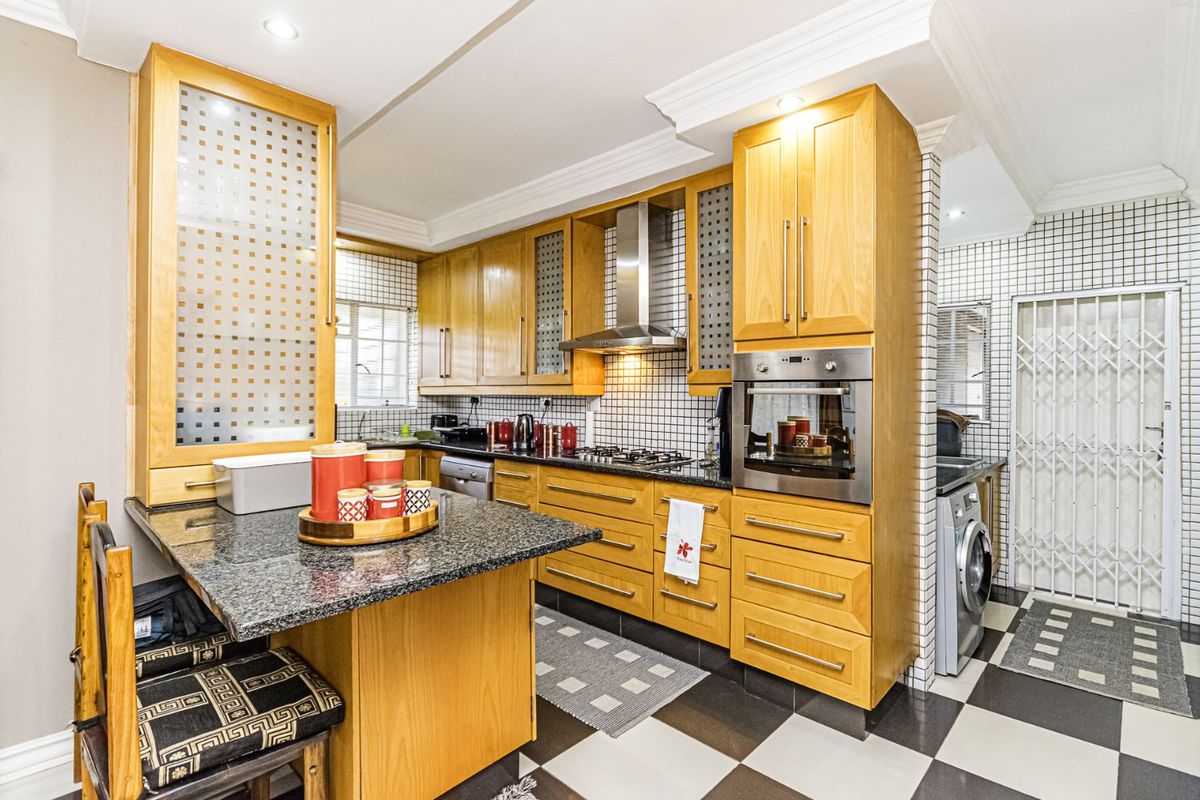 A well-maintained kitchen featuring light wood cabinetry, granite countertops, a built-in oven, gas hob, extractor fan, and a breakfast nook.