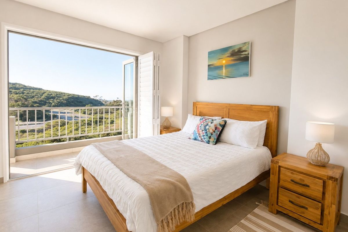 Bright bedroom featuring tiled flooring, recessed lighting, and large glass doors opening onto a private balcony with scenic landscape views.