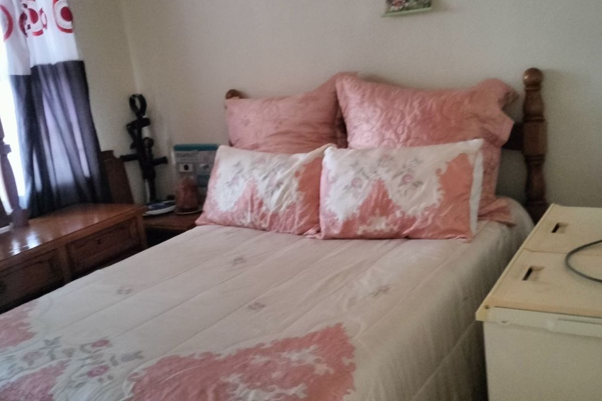 A bedroom featuring a wooden bed frame and a matching wooden dresser with an integrated mirror.