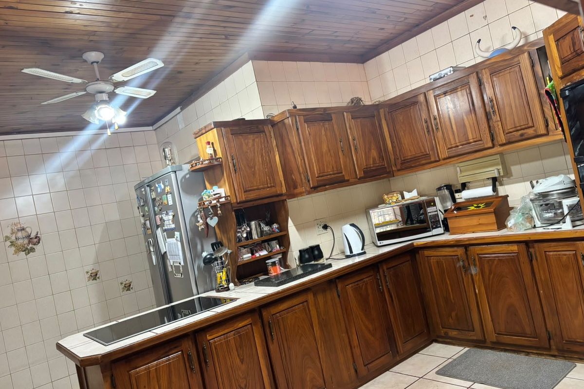 A functional kitchen featuring traditional wooden cabinetry, tiled backsplash, and a wooden ceiling with an integrated fan.